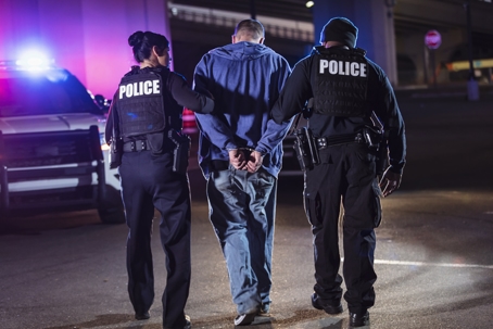 man being arrested and walked to jail by police